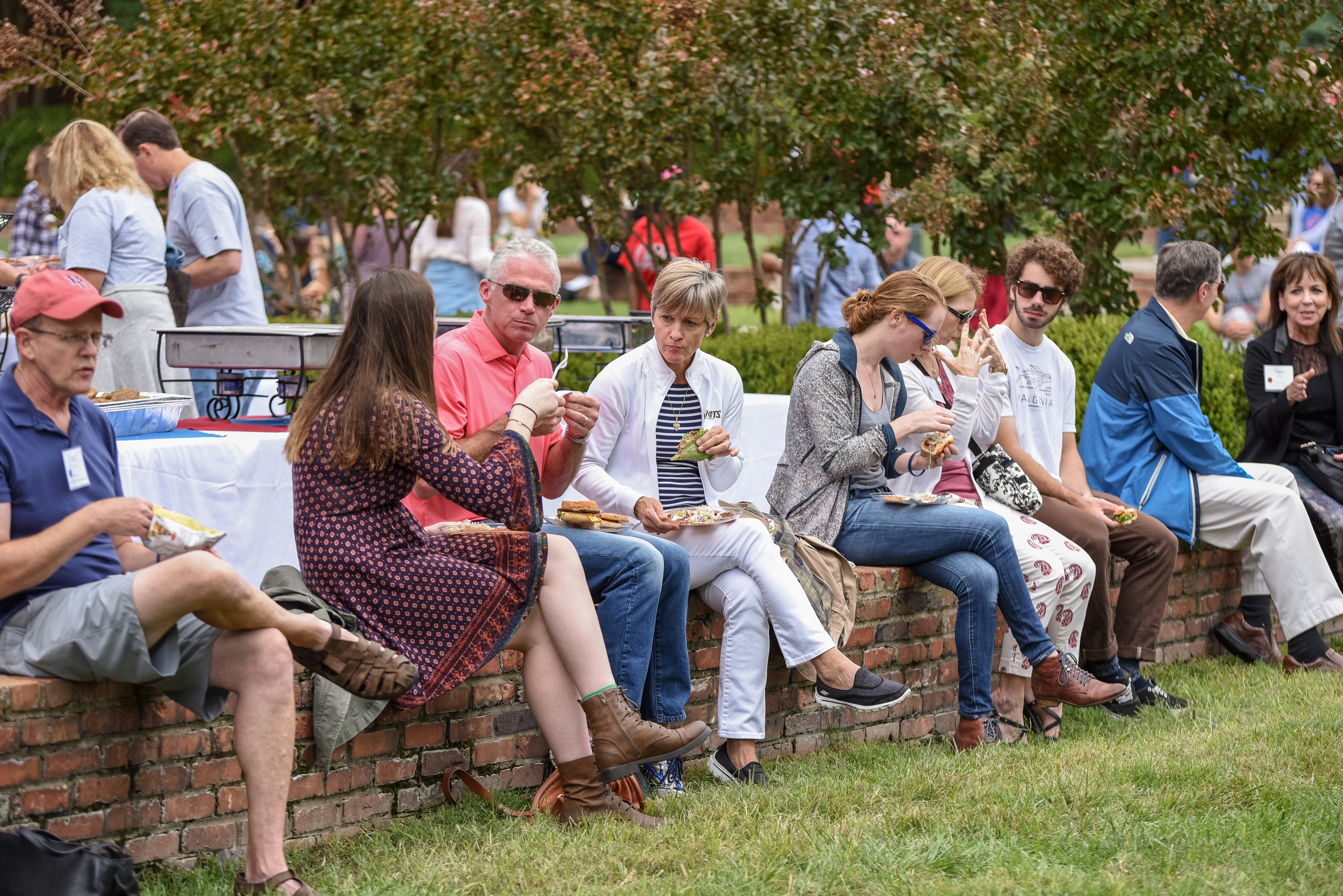 Parents sit on the lawn and enjoy a meal at Parents and Family Weekend.