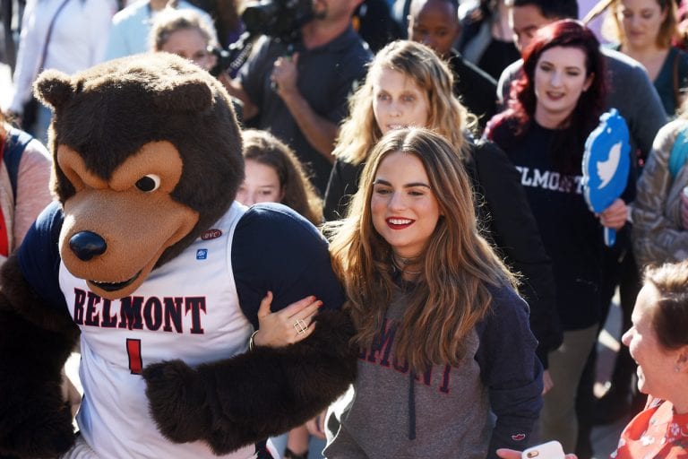 JoJo linking arms with Belmont's mascot in a crowd of students