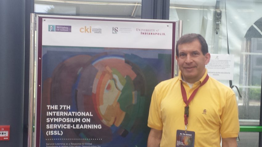Stewart in front of a sign at the International Symposium.