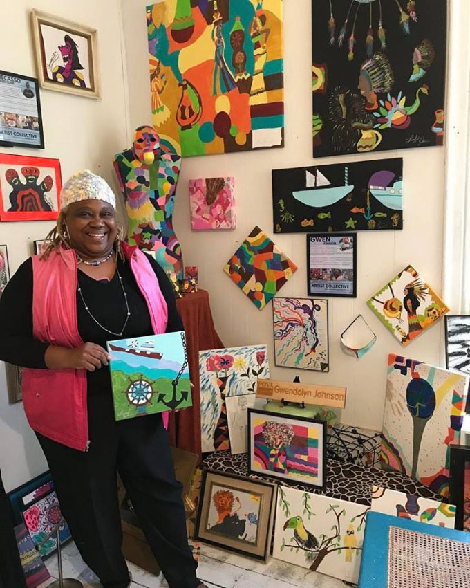 An artist showcases her piece--smiles proudly in front of the pieces she has created