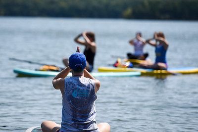 Students in yoga poses on paddleboards on a lake