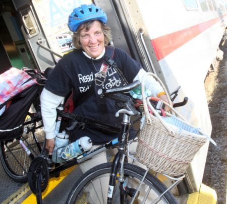 Sally Robertson smiling on bike, wearing library tshirt