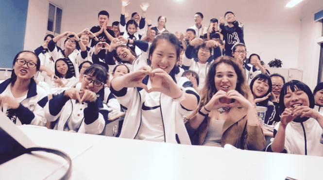 Students holding out their hands in the shape of hearts toward the camera