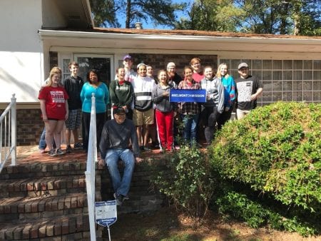 Students stand on the porch of the woman's home they served. 