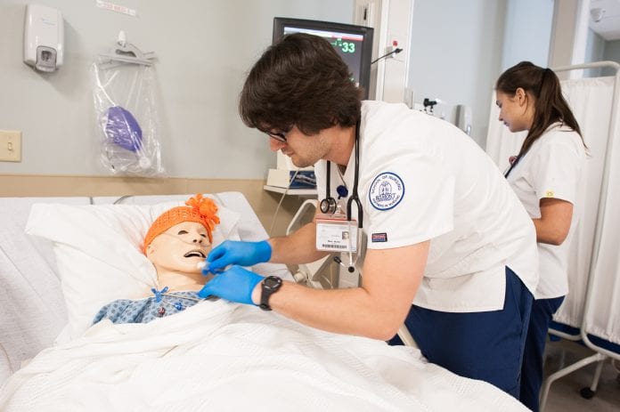A nursing student works along a simulator on Belmont's' campus.