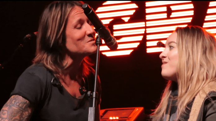 Ashley Sorenson sings into microphone with Keith Urban