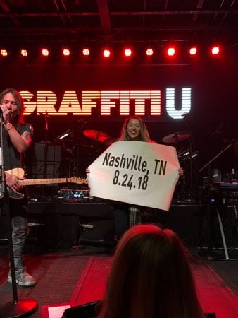 Ashley Sorenson holding sign that says "Nashville, TN 8.24.18"