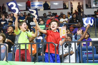 kids cheering from the basketball stands, holding signs with the number 3