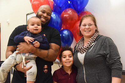 Family standing in front of balloons, smiling