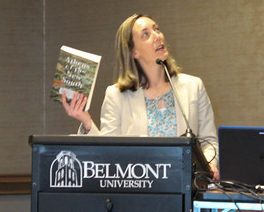 Dr. Mary Ellen Pethel, holding her book and looking up at a screen