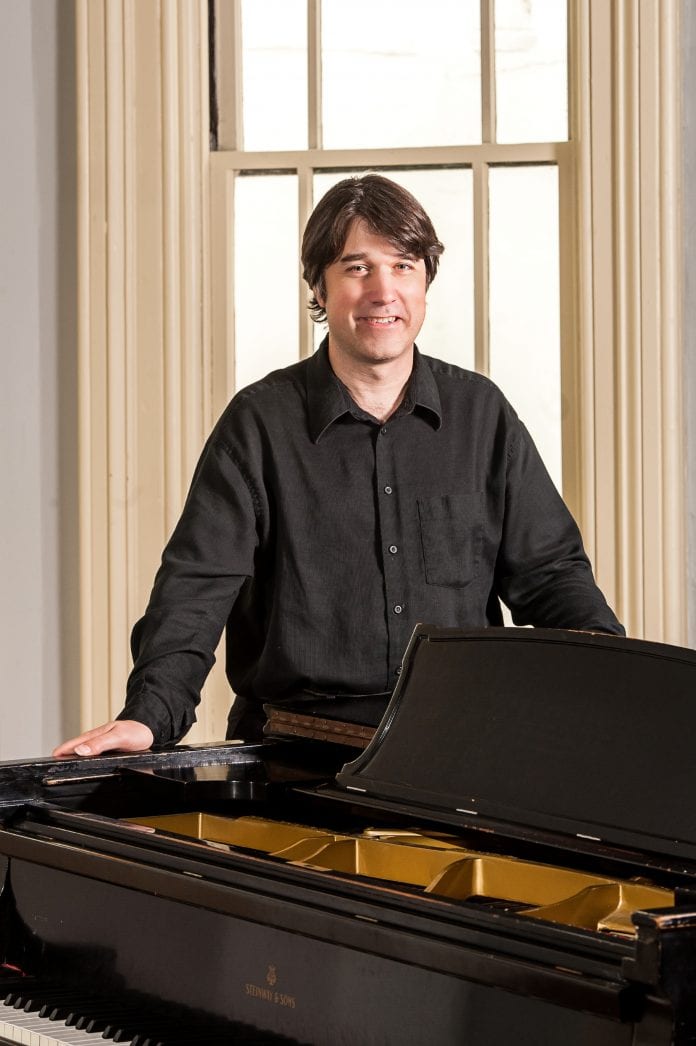 Mark Volker standing behind a piano