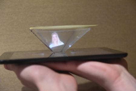 A student holds the hologram he made in his hand.