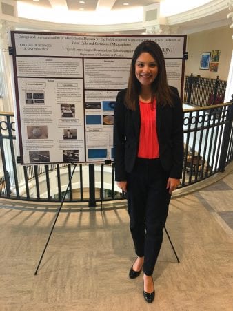 Crystal Lemus, a student, stands in front of her research poster 