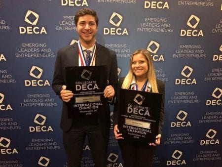 two students posing with winners plaque