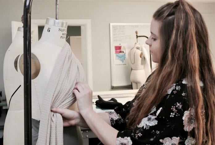 student pinning fabric to a dress form