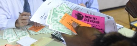 A poverty simulation participant holds the money, vouchers she was given.