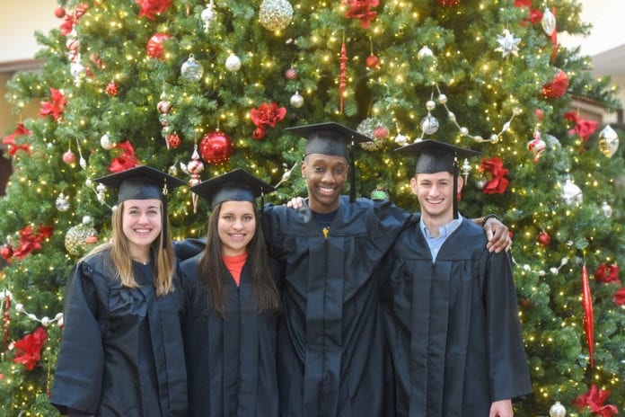 4 graduates in front of Christmas tree