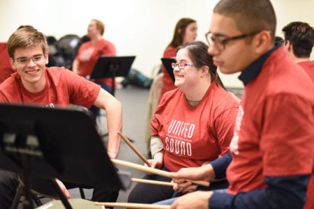 Young adult smiles as she learns percussion instrument