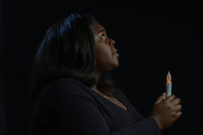 Student Holds Candle against dark background