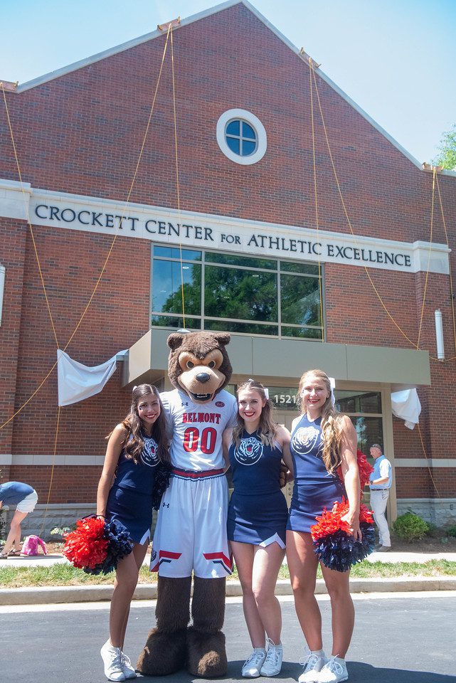Cheerleaders and Bruiser mascot pose in front of new building