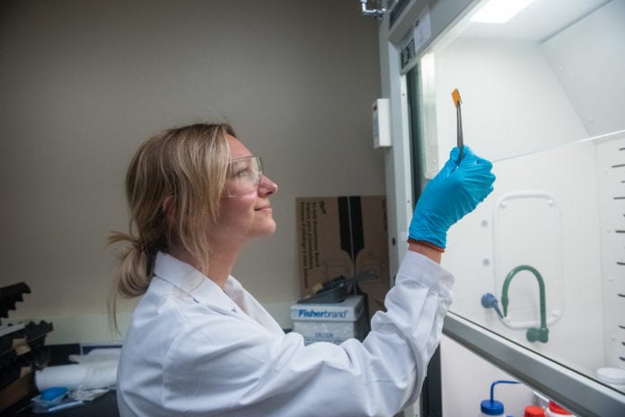 student holds up research sample