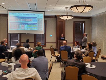 Attendees at a College of Medicine Roundtable event sit at conference room tables listening to a presentation. 