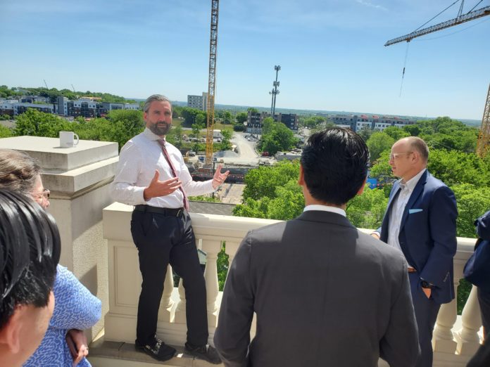 Dr. Andy Michel, Assistant Professor of Psychiatry, Clinical Educator, stands on balcony overlooking future site of College of Medicine with guests.