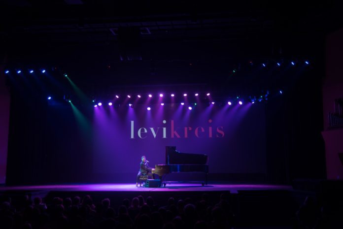 Levi Kreis plays piano on stage at his senior show.