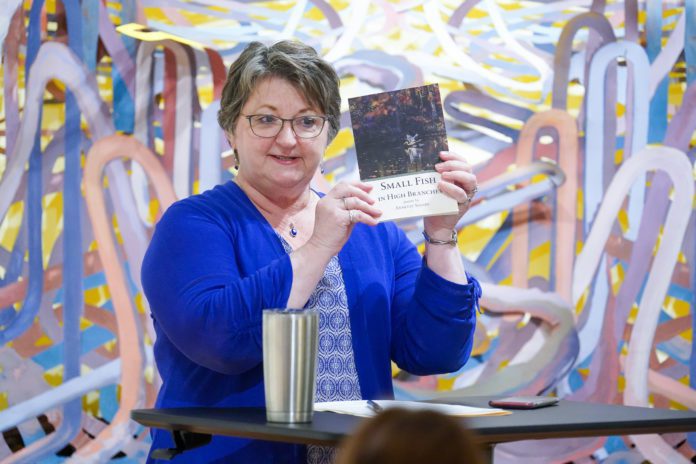 Professor Annette Sisson holds up her new book of poetry at an author talk.