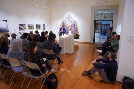 Professor Annette Sisson stands in front of a crowd at Bunch Library and reads from her new book of poetry.