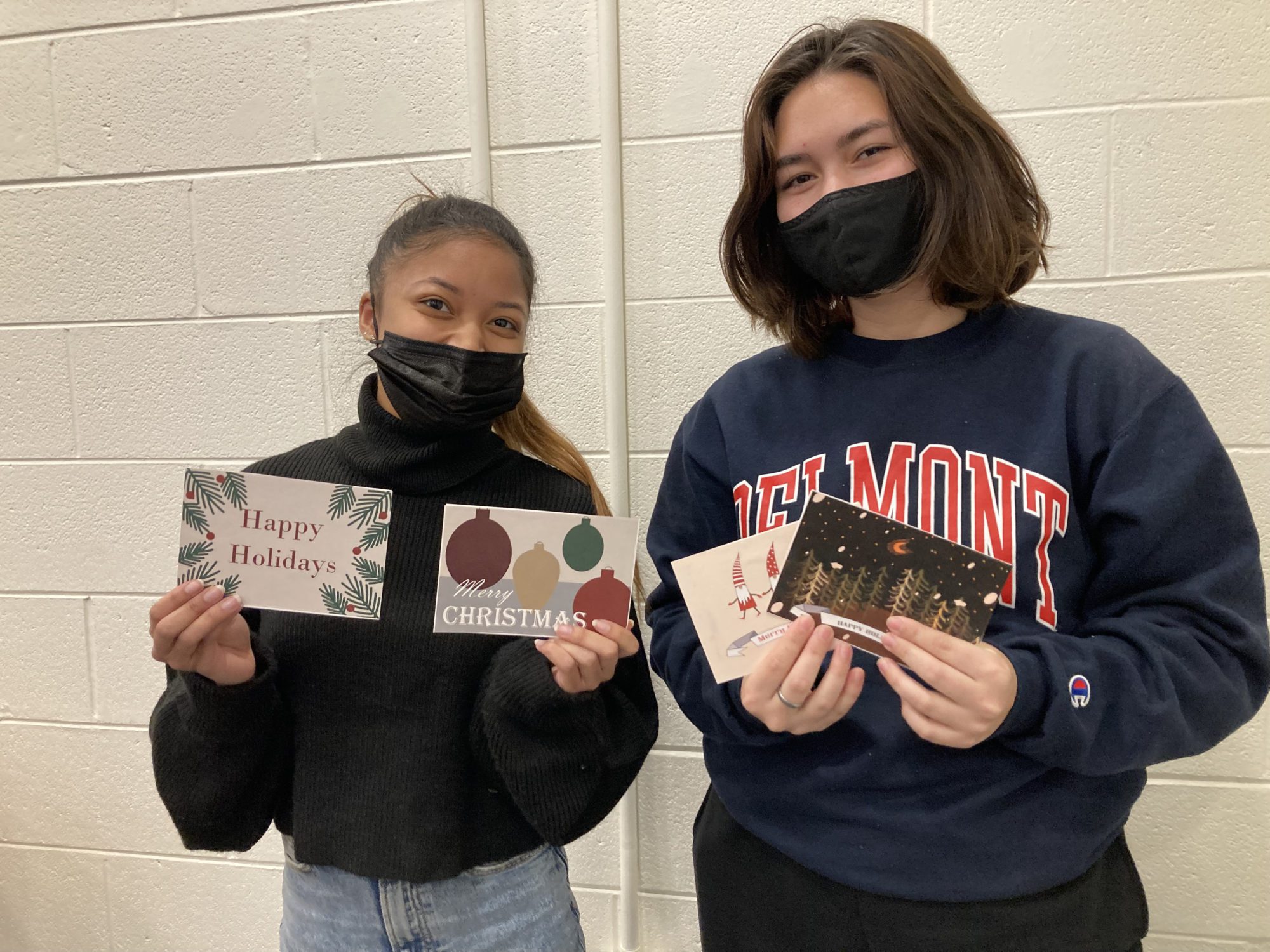 Students hold up Christmas cards they've handwritten and will send to seniors to combat social isolation.