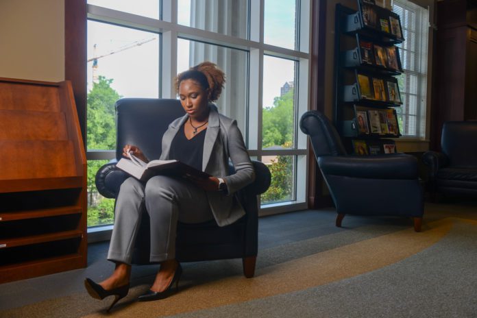women sits in a chair reading a book in a law library